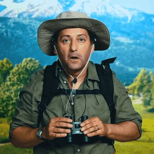 A GIF of a man wearing a hat and rucksack lifting binoculars to his eyes