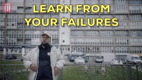 Man leaning up against a fence with large building in background, saying, Learn from your failures.