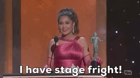 Salma Hayek, dressed in an evening gown on stage, speaks into microphone. She says, 'I have stage fright!' 