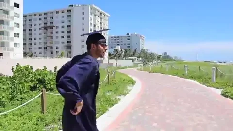 Man dancing in a graduation cap and gown.