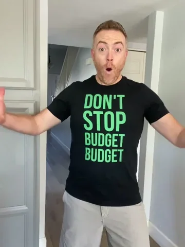 A man wearing a black shirt with the words 'Don't Stop. Budget. Budget' in green letters, doing confident body movements.