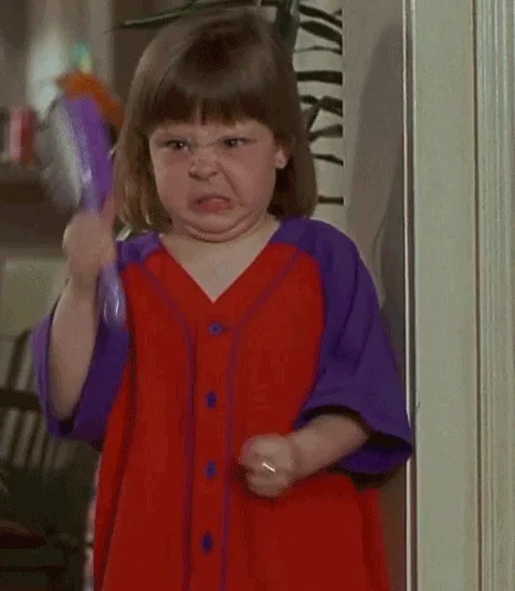 An angry child waving a hairbrush in a threatening manner.