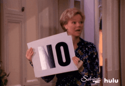 A woman holds up a sign that says 'No'. She drops it to expose another 'No' sign. She repeats this over and over.