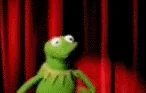 Kermit the Frog wildly flailing his arms in front of red curtains, acting silly and overwhelmed.