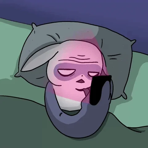 A slight flashing on Yoda-like creature’s face as it looks at its phone in bed.