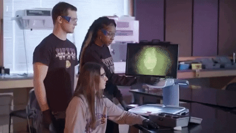 Three young forensic scientists analyzing a finger print on a computer screen