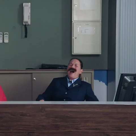 A person laughing loudly behind desk.  