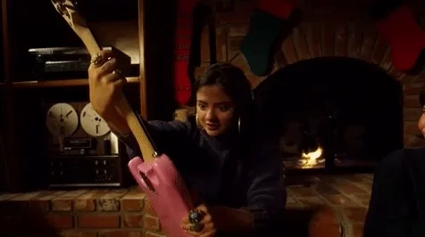 A young woman hugs a pink electric guitar.