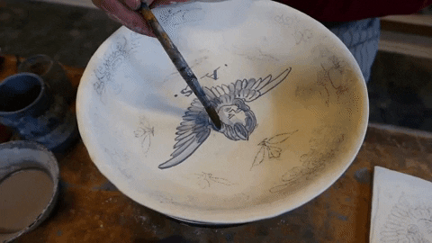 A ceramicist painting a design on a bowl