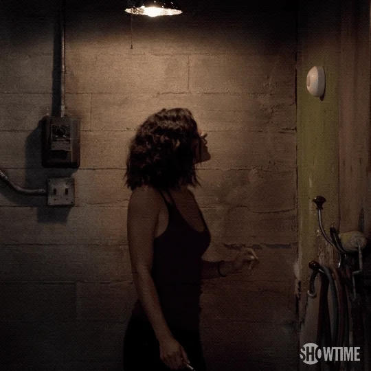 A woman turns on a light switch in a basement.