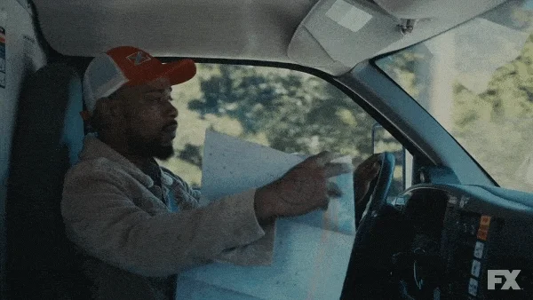 A man driving while looking at a paper map.
