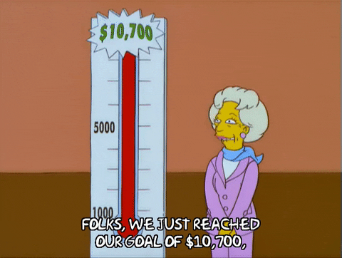 A Simpson's character in front of a donation tracking display announcing that a fundraising goal has been reached.