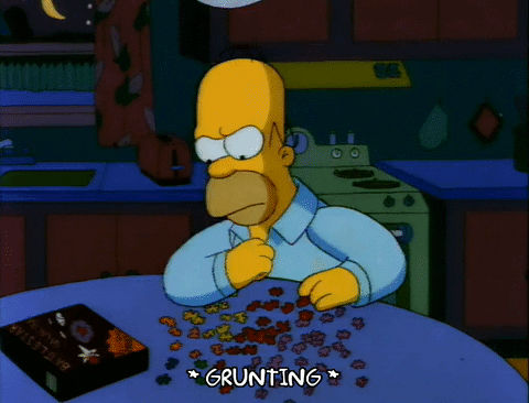 Homer Simpson slams his hand on the table in frustration as he completes a jigsaw puzzle