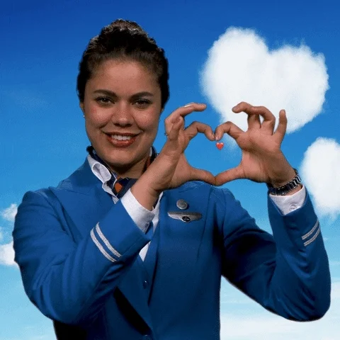 A flight attendant makes a heart with her hand.