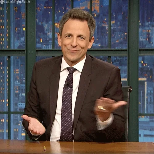 Television host, Seth Meyers, gestures with his hands as if weighing two options. 