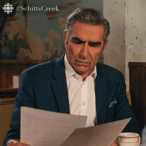Eugene Levy from Schitt's Creek looks at paperwork and is confused. He says, 