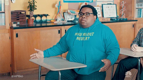 A student at a desk in a classroom looks confused.