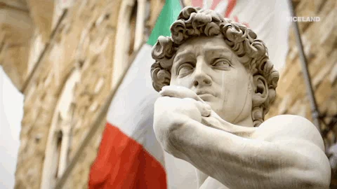Statue of David with Italian flag waving in the background