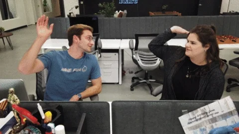 Two people at a desk in a study room high fiving each other. The text reads: "We can do this!"