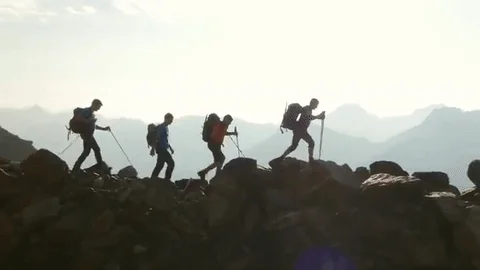 A group of climbers hiking along a ridge with hiking poles.