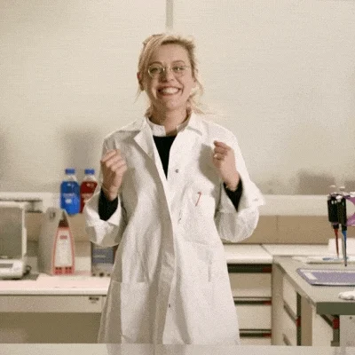 Woman in lab jumping for joy.