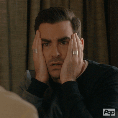 David from Schitt's Creek clutching his face with a 'what?!' expression.