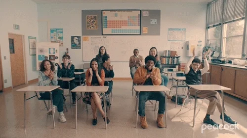 Nine students in a classroom applauding 