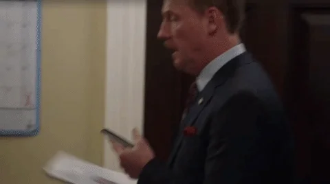 A man running through a semi-crowded hallway in a rush.