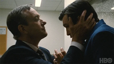 GIF: Man in suit kisses forehead of another man in a suit.