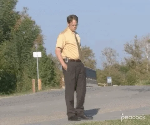 Dwight Schrute from The Office stands on a road, brooding and wondering.