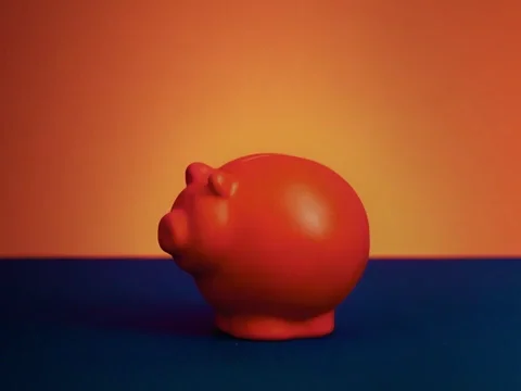 A hand putting a coin in in a piggy bank.