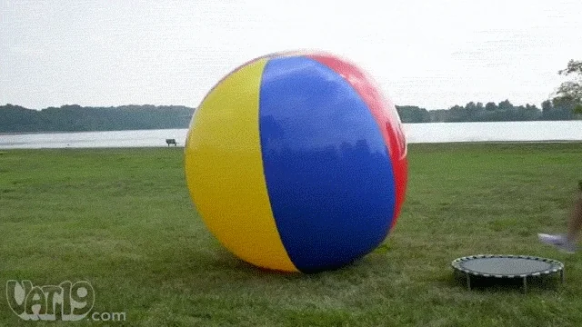 A person trying to balance on a giant ball.
