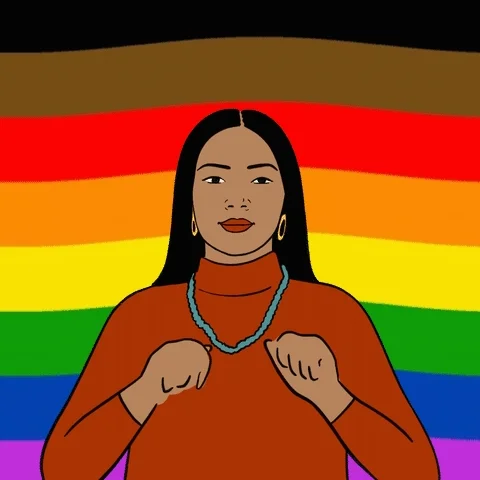 A woman making a heart with her fingers with pride flag moving in the background.