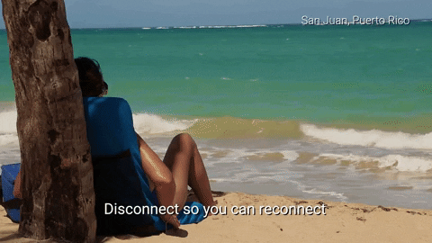 A person leaning against a tree on a beach. The text: Disconnect so you can reconnect