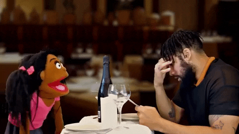 A muppet and a man is on a date. The muppet is talking nonstop, but the man is staring at the menu ignoring her.