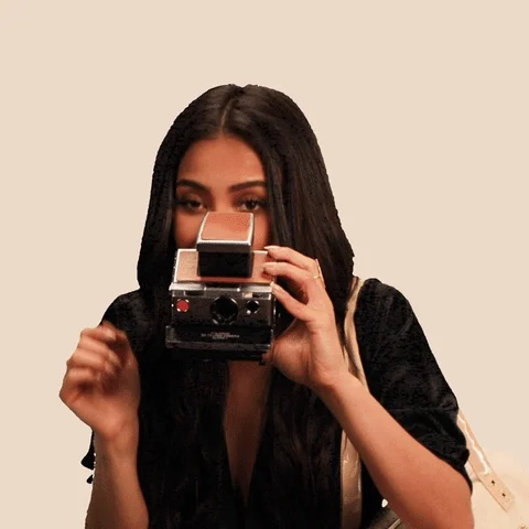 Shay Mitchell taking photos with a Polaroid camera.
