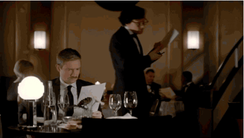 A waiter attending to a client at a fancy restaurant