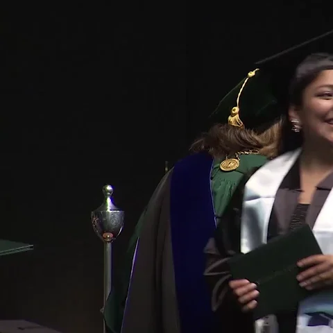 Woman walking across stage with her degree in hand