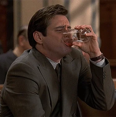 Jim Carrey aggressively throws his head back to gulp water, then spits it all over his chin. He yells, "Oh, come on!"