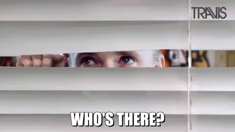 A white male peeking through curtain blinds with the caption 'Who's there?'