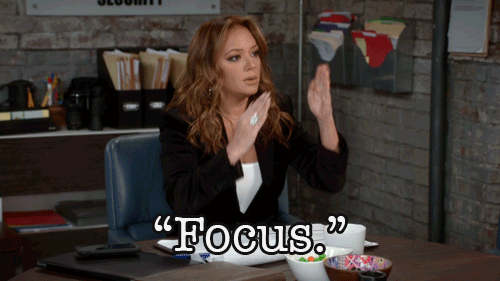A woman at a desk motioning with her hands. She says, 'Focus.'