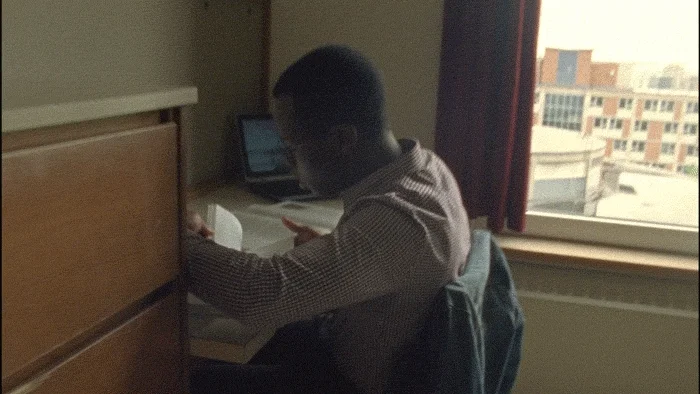 A young man is quickly flipping through the pages of a book. 