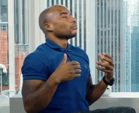 A man is closing his eyes and taking a deep breath in an office.
