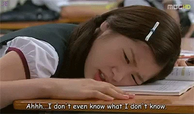 A girl rests her cheek on an open book on a table and says 