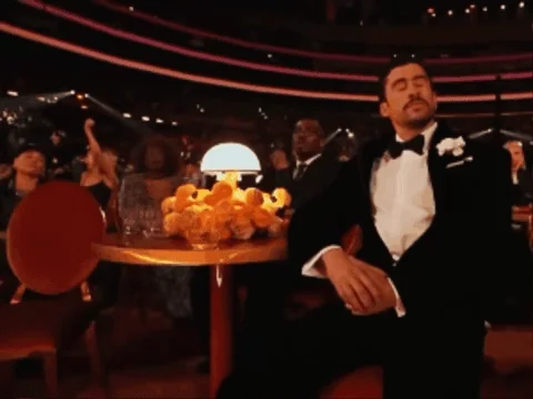 Bad Bunny covering his face with his hand in a dramatic face-palm, appearing overwhelmed.