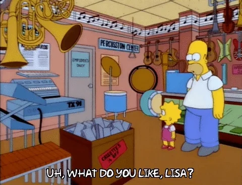 Homer and Lisa from 'The Simpsons' are standing in a musical instrument shop. Homer asks Lisa which instrument she likes.