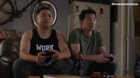 Two guys sitting on a couch playing video games without talking to each other.