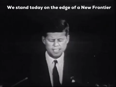 John F. Kennedy giving a speech, saying 'We stand today on the edge of a new frontier.'