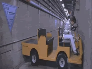 Austin Powers trying to turn a factory cart around in a narrow hallway.