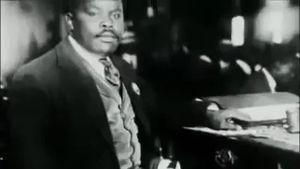 A camera zooming in on an archival photo of Marcus Garvey.